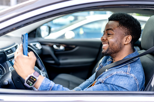 On the road, a young African American man is engaged in a video call on his mobile phone, demonstrating the use of technology to stay connected during his journey