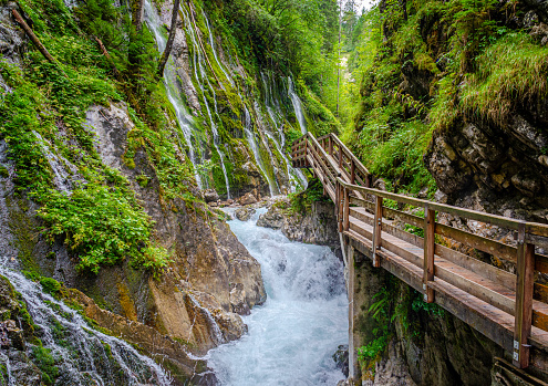 Wanderweg auf einem Holzsteg mit Wildwasser und Wasserfällen in der wildromantischen Wimbachklamm im Nationalpark Berchtesgaden