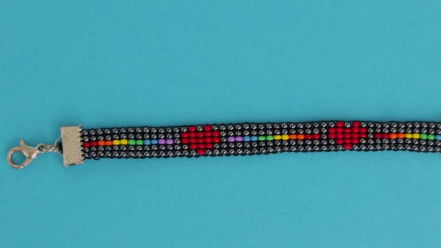 Handmade LGBT bead pattern necklace over turquoise background. Close up