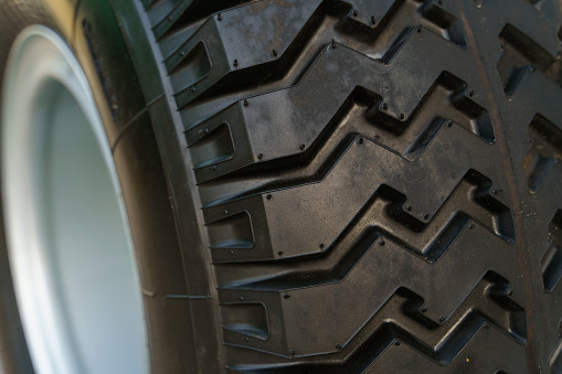 Detailed view of a tire mounted on a vehicle, showcasing the tread pattern and sidewall. The tire is dirty, indicating recent use.