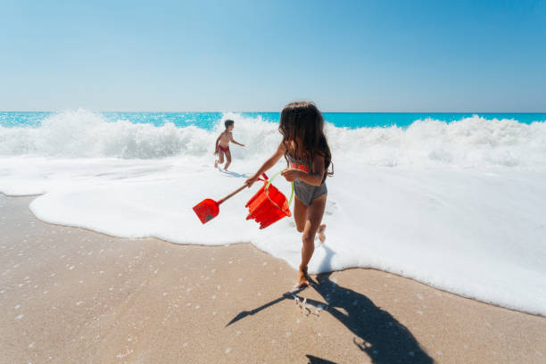 Playful children running and having fun on the waves on their summer vacation