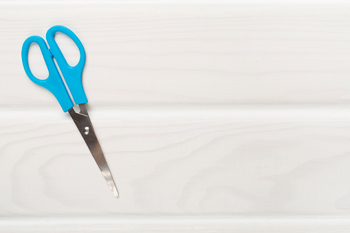Blue scissors on wooden backgroung, top view