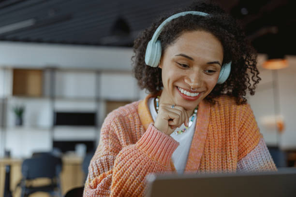 istock A happy woman smiles while looking at a laptop computer with audio equipment 2081925737