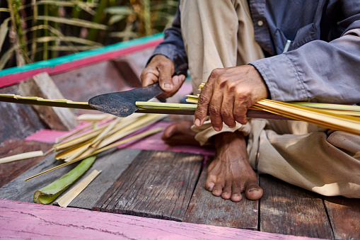 A fisherman makes a roof out of palm leaves in Thailand