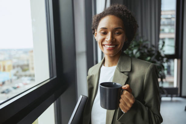 istock A whitecollar worker gazes out a window with a cup of coffee, smiling 2081935938