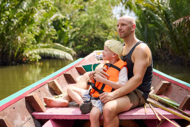 istock A father sits with his son on a longtail boat during a trip on a canal 2081949755