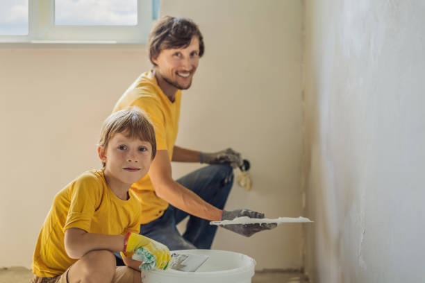 man with his son makes repairs at home, he teaches children to plaster the walls with a spatula in his hands - plaster plasterer work tool child imagens e fotografias de stock