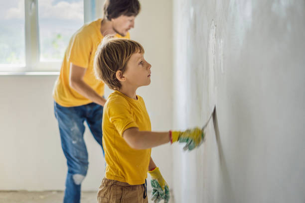 man with his son makes repairs at home, he teaches children to plaster the walls with a spatula in his hands - plaster plasterer work tool child imagens e fotografias de stock