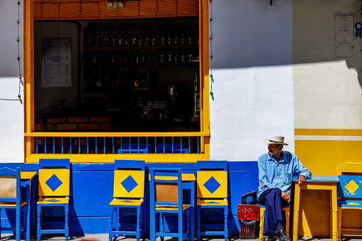 Jardin, Colombia - January 13, 2023: Shoeshiner takes a break at an outside table of a cafe