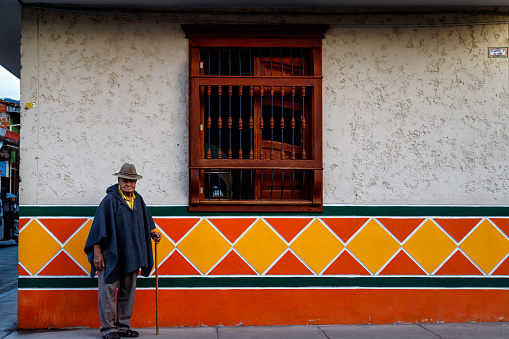 Jardin, Colombia - January 12, 2023: Older man with cane stops to take a break on a corner of the village