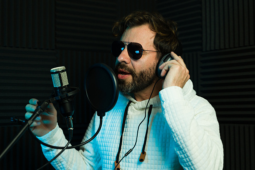 Famouse lead singer wearing sunglasses and recording a song in a soundproof studio