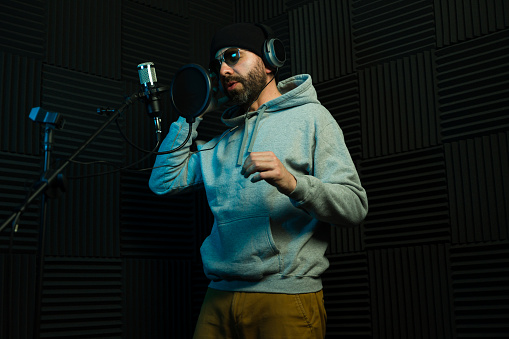 Trendy male singer with a beard, performing in a soundproof recording studio