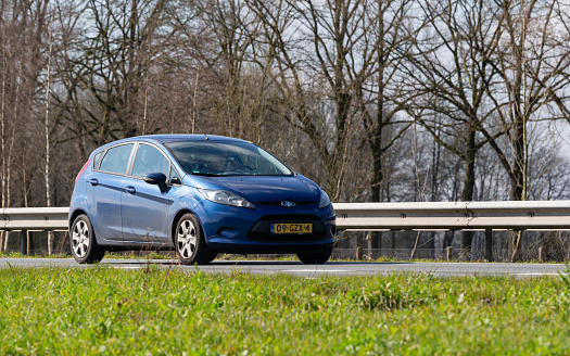 Netherlands, Overijssel, Twente, Wierden, March 19th 2023, side/front view close-up of a Dutch blue 2008  Ford 5th generation Fiesta hatchback driving on the N36 at Wierden, the Fiesta has been made by American car manufacturer Ford from 1976-2023, the N36 is a 36 kilometer long highway from Wierden to Ommen