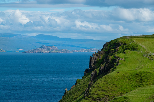 Grassy cliffs and exceptional views of nearby islands and rugged ocean coastline. Stunning landscape and constantly changing weather conditions on scenic Isle of Skye in northern part of Scotland.