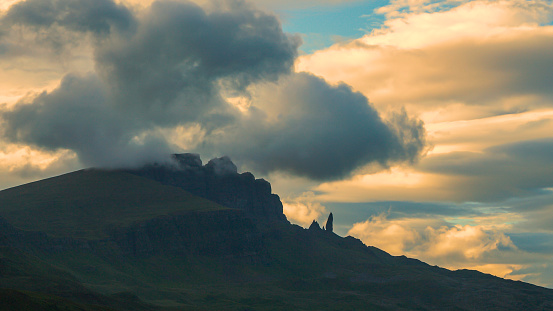 SILHOUETTE: Beautiful outline of iconic mountain The Storr shrouded in clouds. Majestic scenery with dramatic golden coloured clouds rolling around the famous mountaintop on picturesque Isle of Skye.