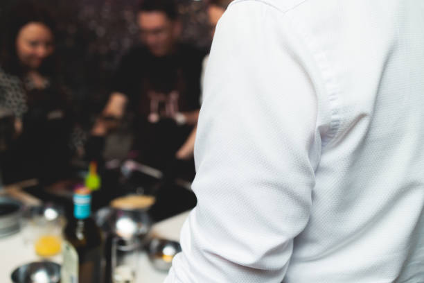 Group of guests in a cooking class studio, adults preparing different dishes in the kitchen together, people in aprons learn on culinary master class, chef uniform, hands in gloves, italian cuisine