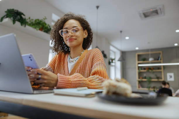 istock a freelancer woman is sitting at a table using a laptop and a cell phone 2082011612
