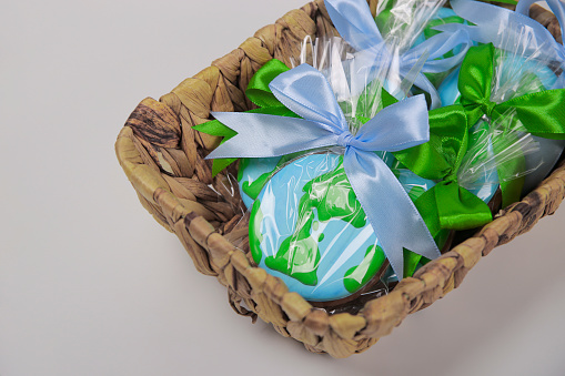 A basket filled with cookies in shape of Earth on green backdrop. Earth Day concept.