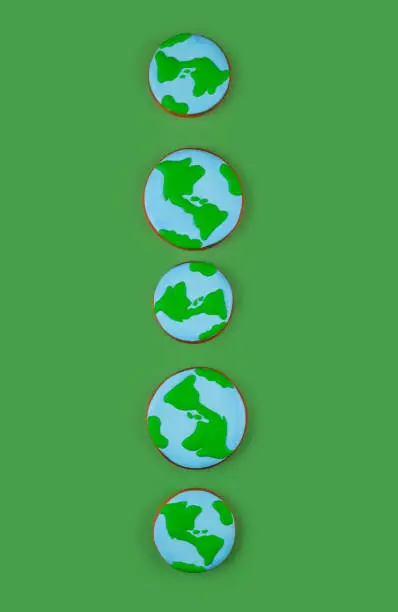 Photo of Earth Day concept. Cookies in shape of Earth on green backdrop.