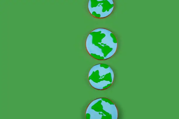 Photo of Earth Day concept. Ð¡ookies in shape of Earth on green backdrop. Background with copyspace.