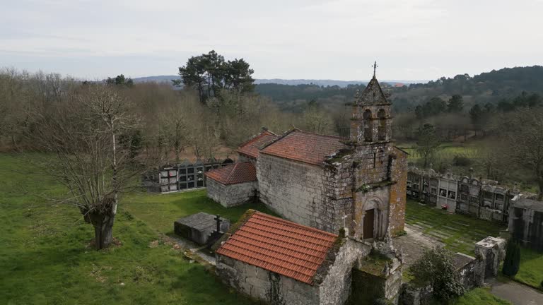 Quaint mossy weathered old chapel surrounded by cemetery urn holders of Church of Santa Maria de Vilela in Punxin Ourense Spain