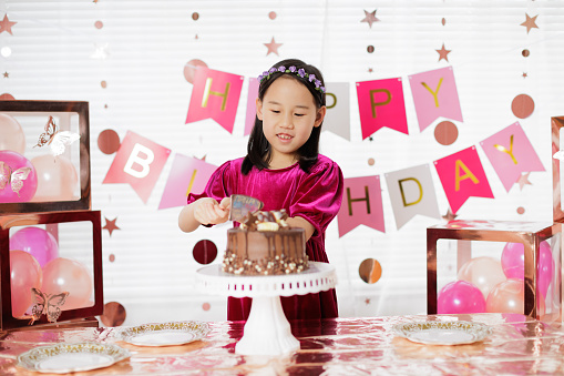medium shot young girl was cutting cake  for celebrating her 8th birthday at home