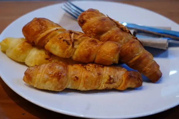 Photo of Close-up of a plate with golden brown croissants on a table.