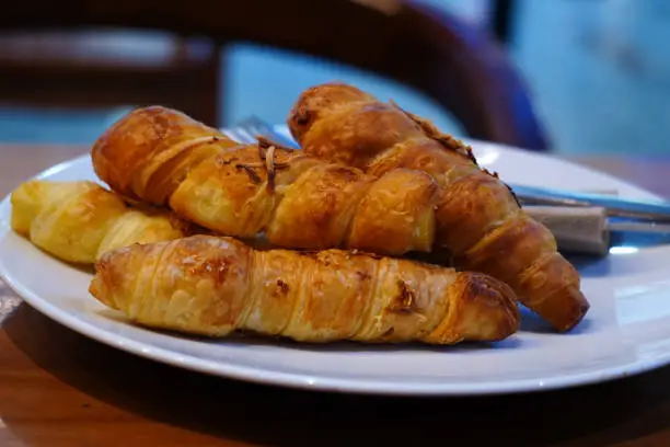 Photo of Close-up of a plate with golden brown croissants on a table.