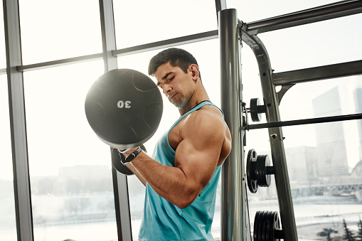 sport, bodybuilding, lifestyle and people concept - young man with barbell flexing muscles and making shoulder press lunge in gym.