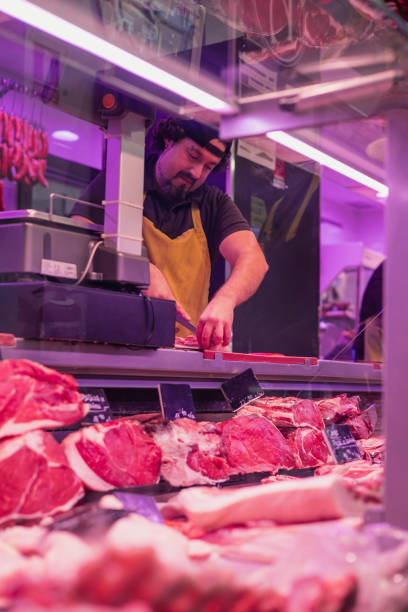 istock vertical portrait Butcher slicing meat behind counter 2082118970