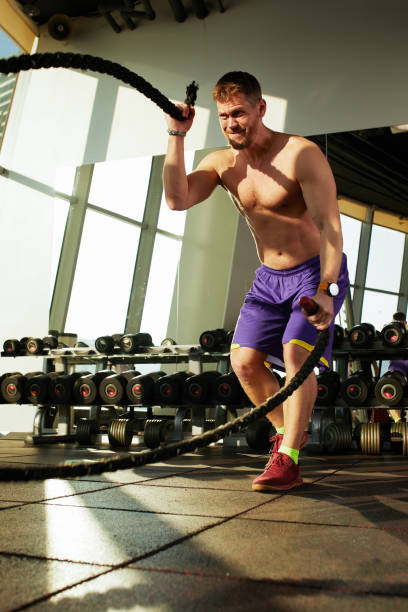 istock Athletic young man with battle rope doing exercise in functional training fitness gym 2082137681