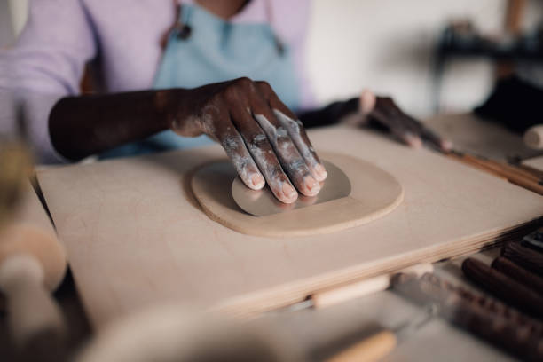 istock Close up of interracial craftswoman's hand using pottery tool for clay 2082171812