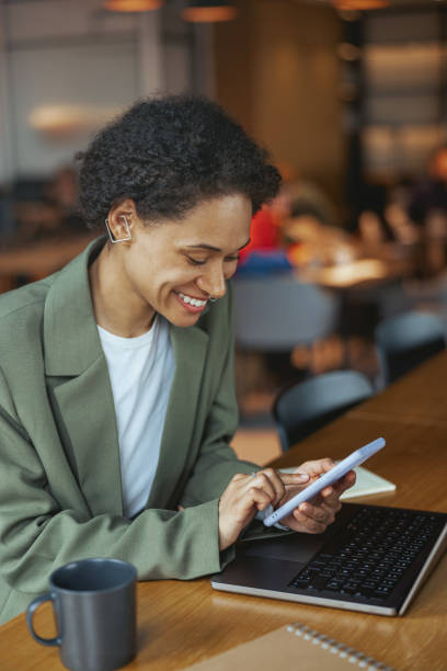 istock A woman sits at a table with a laptop and tablet, smiling in her blazer 2082187616