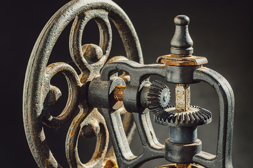 Close-up of Antique coffee bean original grinder metal shake wheel with hand crank. Detail of Old original coffee grinder on dark background, Copy sace, Selective focus.