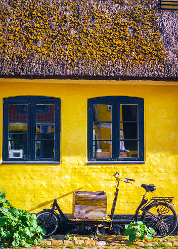 Dragor yellow old fashioned home with windows and elongated bike outside