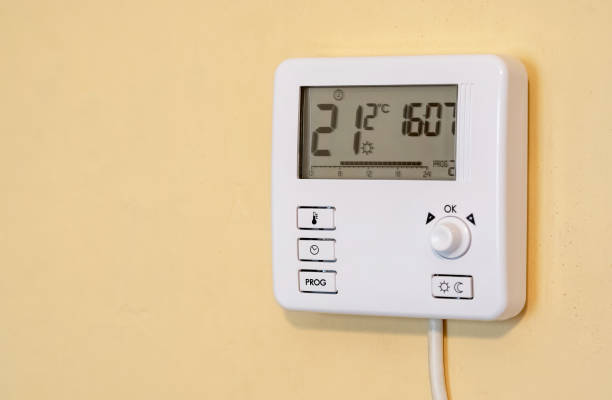istock Modern smart home programmable digital thermostat unit mounted on a yellow wall inside a house, showing the current room temperature and set temperature in a residential apartment setting, nobody 2082288895