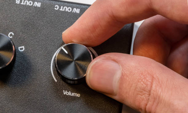 Anonymous man fingers finely tuning a volume knob on a sleek audio device control panel, adjustment of sound levels, gain control, turning music up, or turning down, sound controls abstract concept dedos anónimos del hombre afinando finamente una perilla de volumen en un elegante panel de control del dispositivo de audio, ajuste de los niveles de sonido, control de ganancia, subiendo o bajando la música, concepto abstracto de controles de sonido