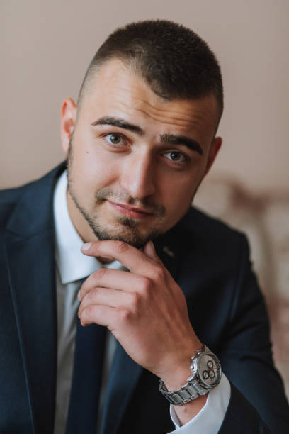 istock Confident elegant handsome guy at home sitting on the couch in a nice dark blue suit. 2082308522
