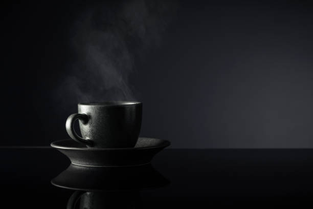 Black cup of coffee on a black reflective background. Copy space.