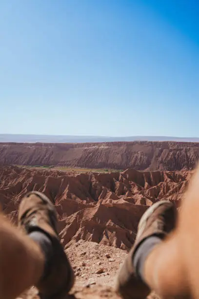 Photo of Pov view of legs of man on the top of a viewpoint in Quebrada de Chulakao in San Pedro de Atacama