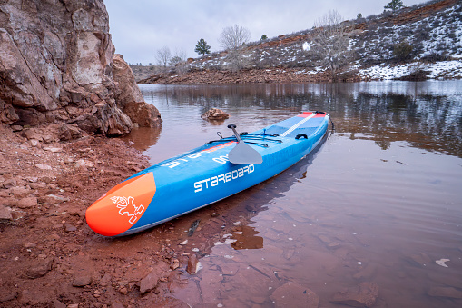 Fort Collins, CO, USA - December 25, 2019: Racing stand up paddleboard by Starboard on a mountain lake - Horsetooth Reservoir at foothills of Rocky Mountains.