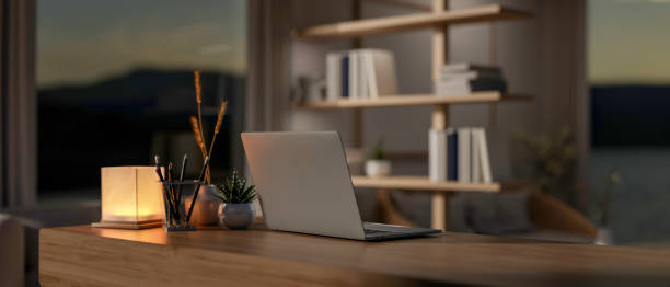 istock A contemporary home office workspace at night features a laptop computer on a wooden desk. 2082373172