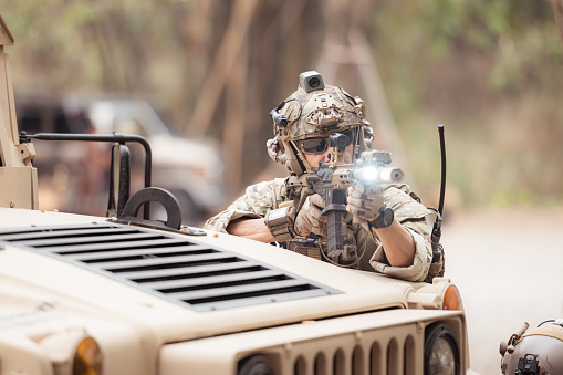 Soldiers in camouflage uniforms hold weapons ready to fire, By hiding on the side military communication vehicle