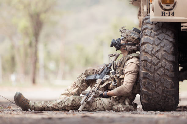 Soldiers in camouflage uniforms hold weapons ready to fire, By hiding on the side military communication vehicle
