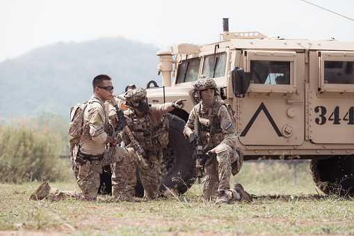 Group of soldiers in camouflage uniforms hold weapons in a jltv car, Plan and prepare for combat training.