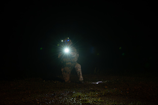 Soldiers in camouflage uniforms hold weapons with patrol missions at night