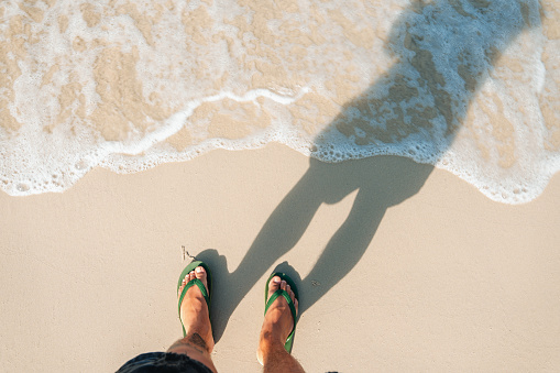 Summer travel concept Feet on the sand and clear sea waves