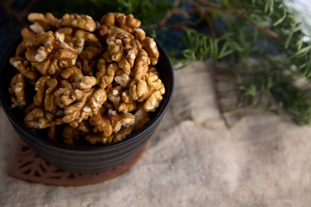 Top view of a delicious walnut in a beautiful interior. A lot of peeled walnuts in a ceramic black plate on a handmade wooden stand on the table