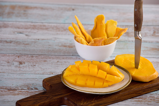 Healthy fruit snack of ripe mango and slices of sweet candied fruit. Close-up on a plate of sliced juicy pulp of tropical sweet mango.