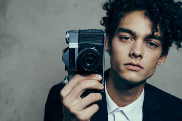 stylish man with camera in hand photography studio curls model portrait. High quality photo